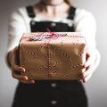 woman holding a christmas gift towards the screen