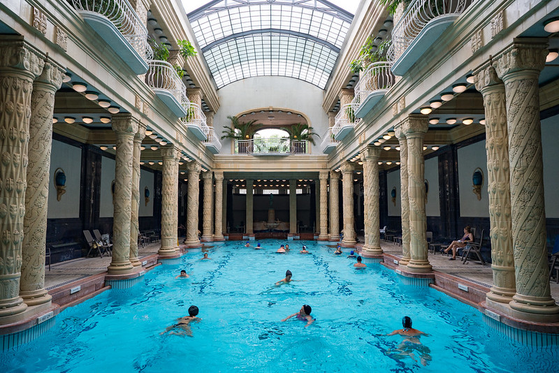 a pool between pillars with people swimming in it