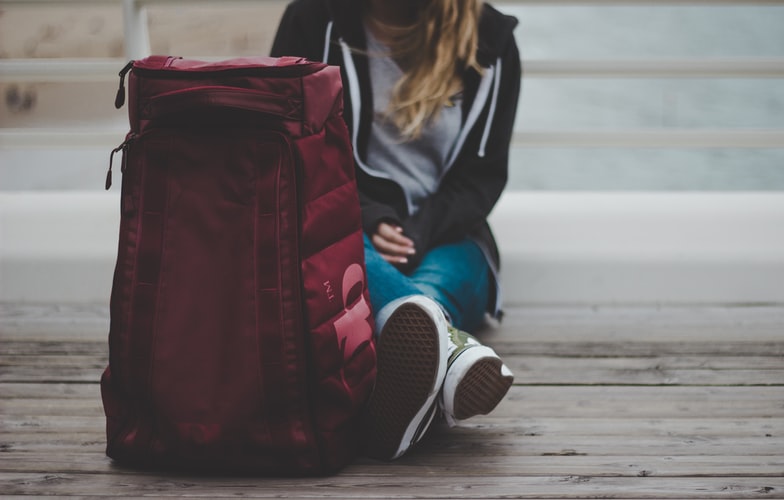 a girl sitting on the ground with a red suitcase next to her