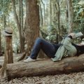 woman lying on a tree trunk reading