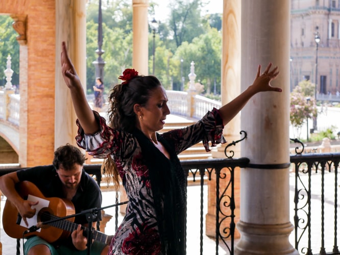 a woman dancing while a man plays the guitar