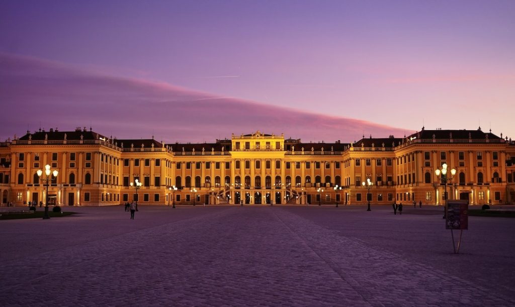 The facade of Schönbrunn Palace against a purple sky at dusk in Vienna, Austria