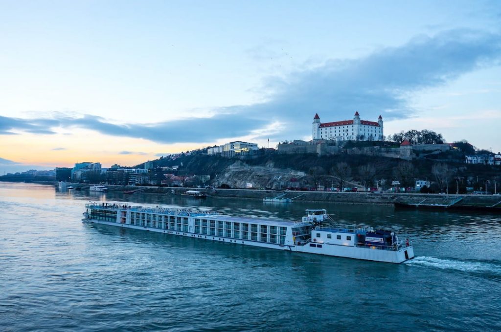 A river cruise ship cruising along the Danube with Bratislava Castle in the background