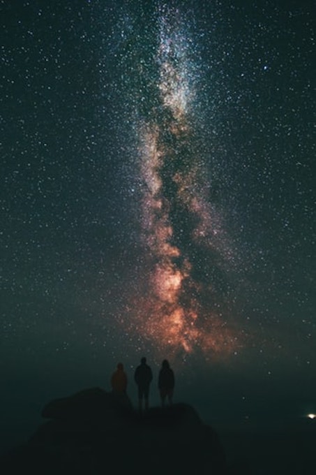 three people looking at the stars and milky way