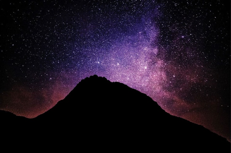 silhouette of mountain under starry night
