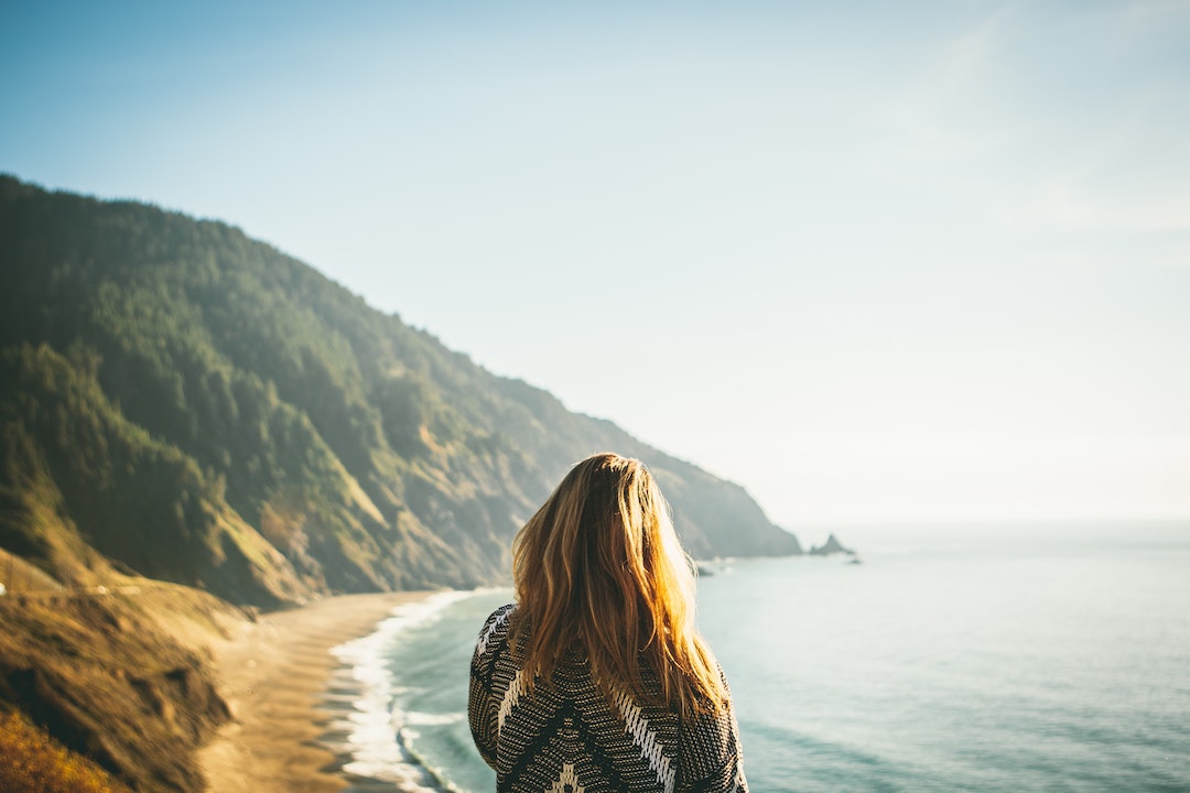 Woman standing in front of a bay with her back facing camera