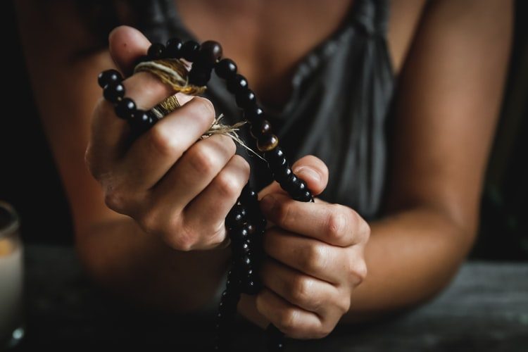 a woman holding prayer beads