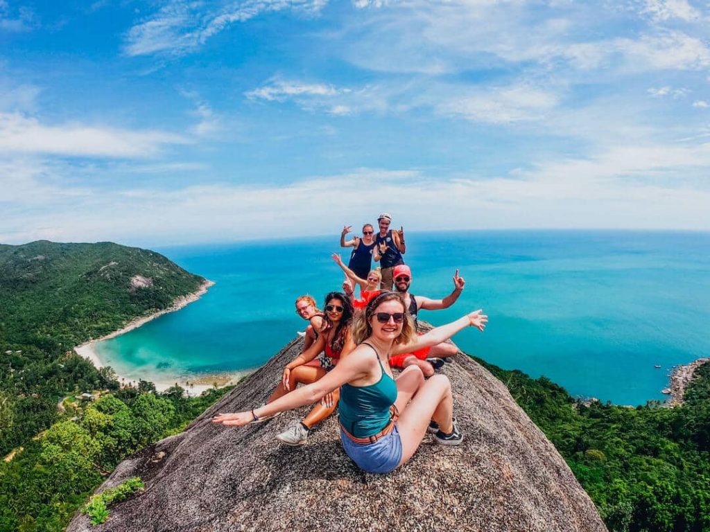 Group of people posing on a lookout point overlooking a beach in Thailand