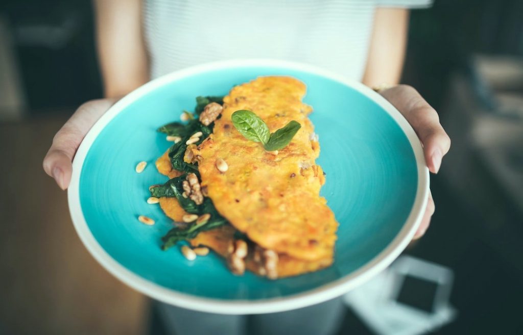 Woman holding a blue plate with an omelette
