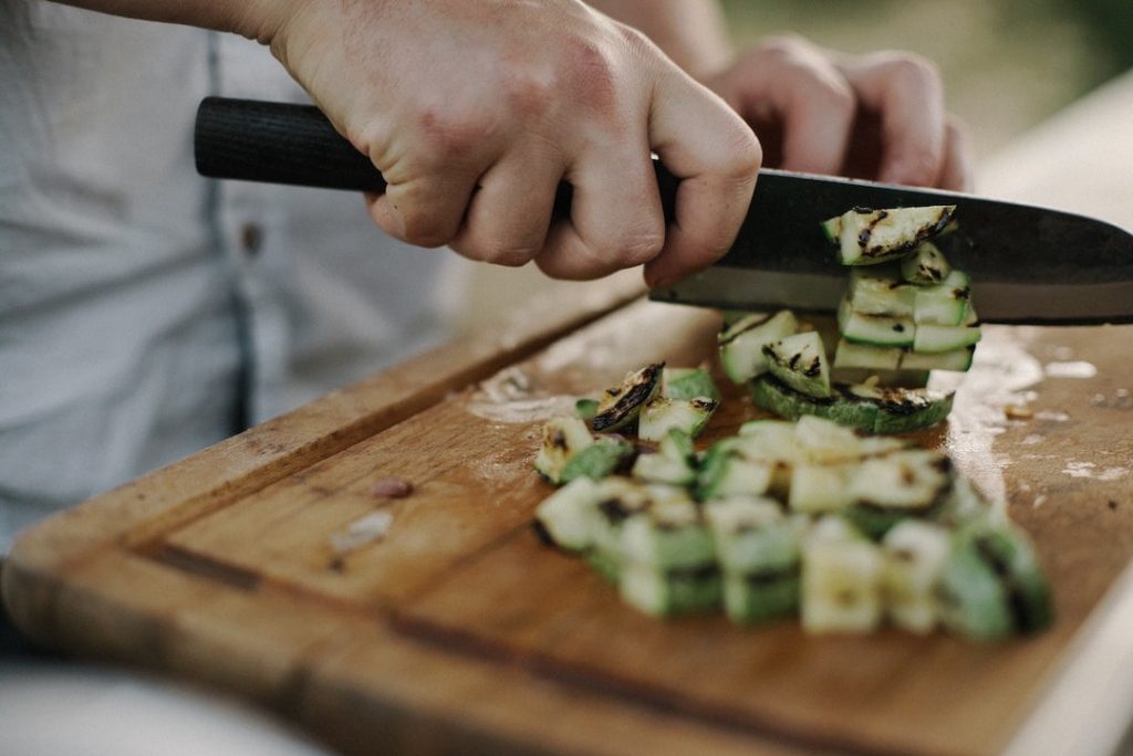 Close up of a person chopping vegetables with a large knife