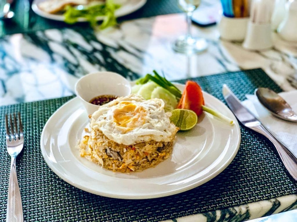 A plate with rice topped with a fried eggs and sauce on the side
