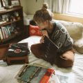 a woman sitting on her bed listening to music