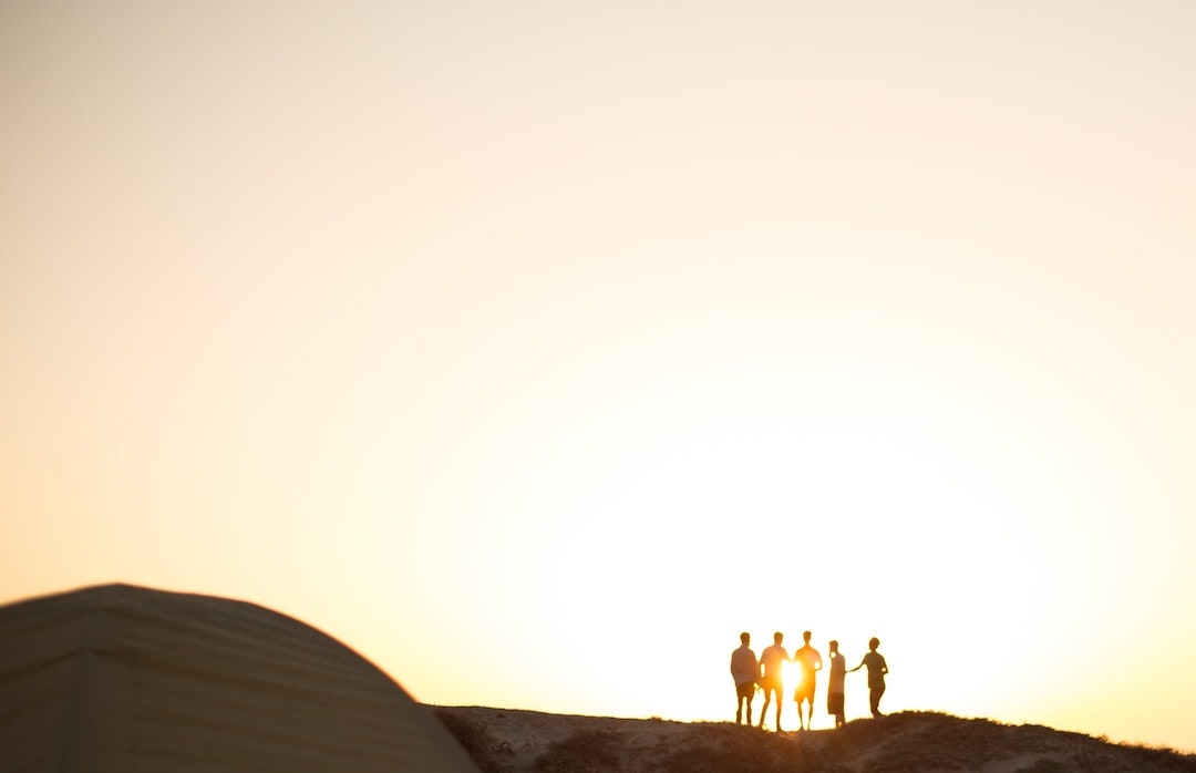 Group of friends standing on sand dunes at sunset