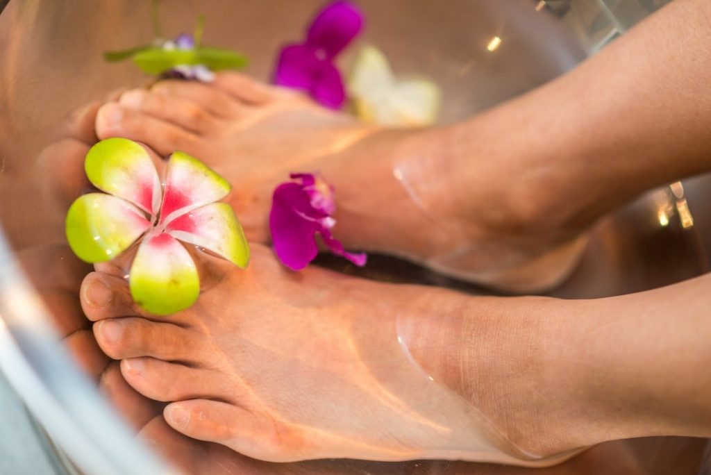 Feet soaking in a basin with flowers