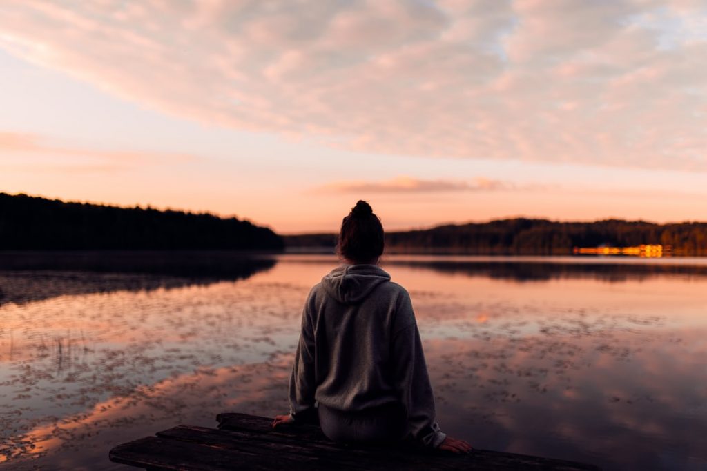 girl sitting on a pier overlooking the lake at sunset