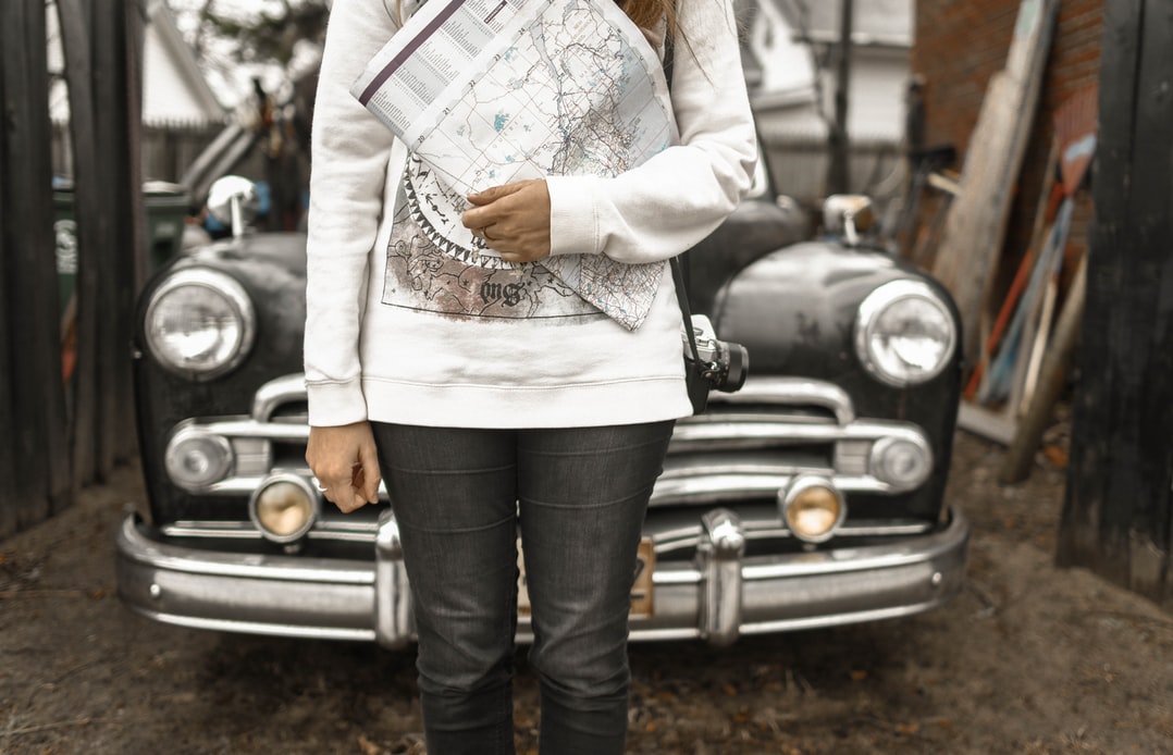 travel personality quiz: woman holding a map in front of her car