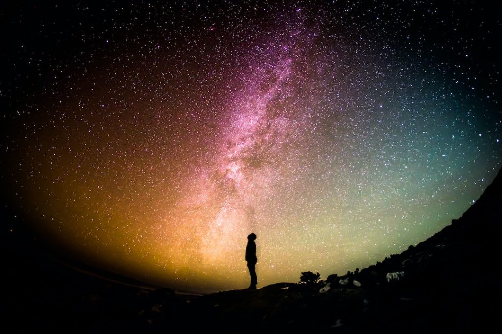 Silhouette of a person looking up at a star filled sky
