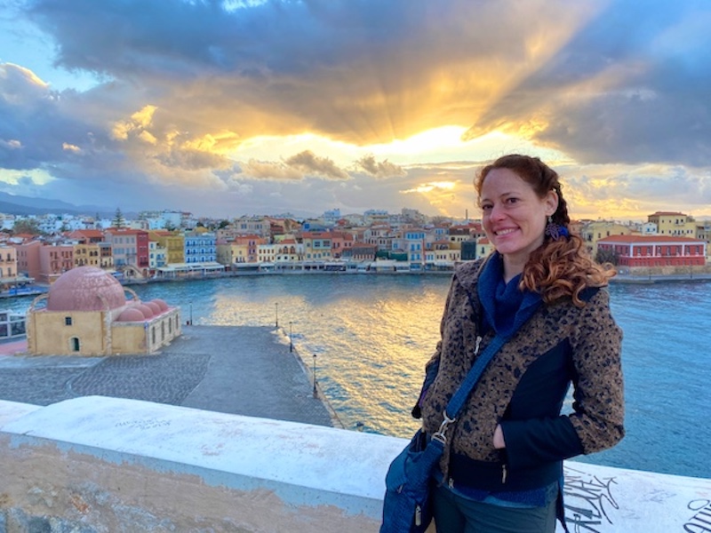 Woman standing in front of sunset in Chania, Greece