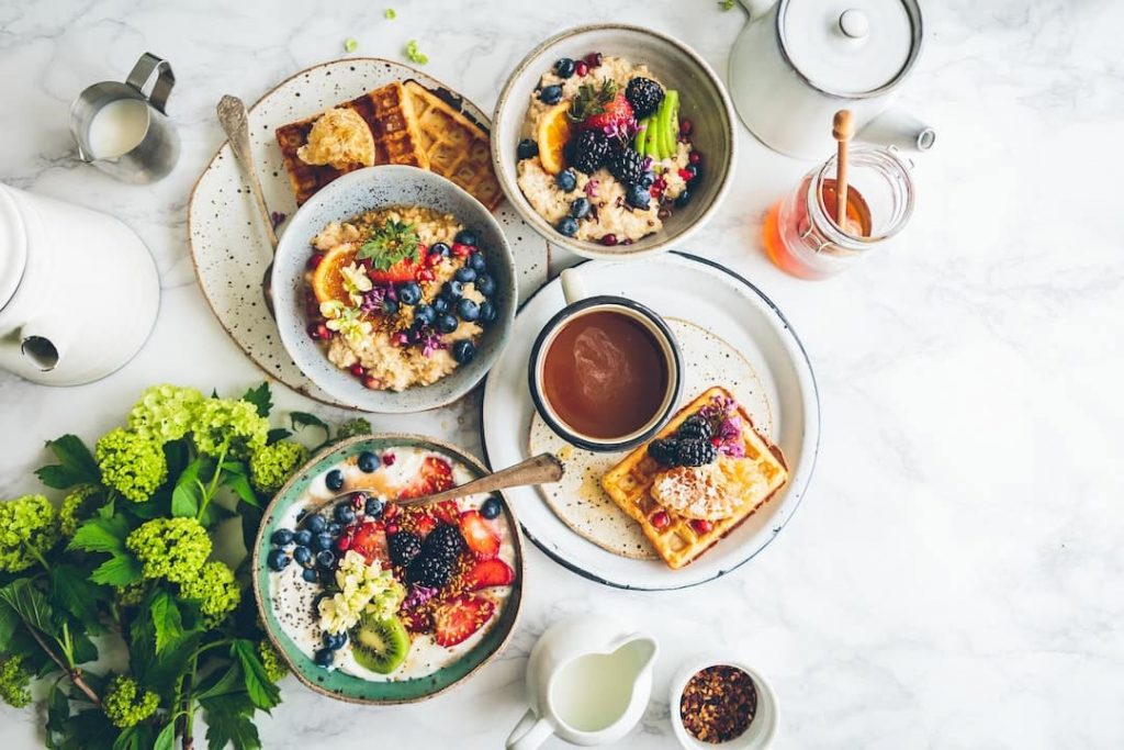Table set with bowls of porridge, waffles, coffee cups, and flowers