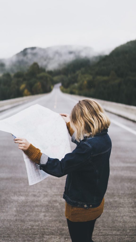 Woman standing in the middle of the road looking down at a map