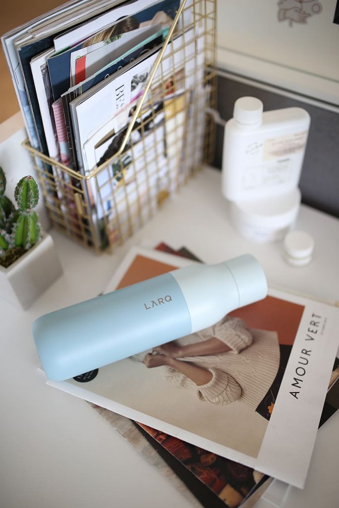 useful travel accessories: a larq bottle on top a pile of magazines