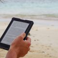 Person holding a kindle on the beach