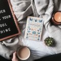 Cup of tea, candle, and hygge book on a bed