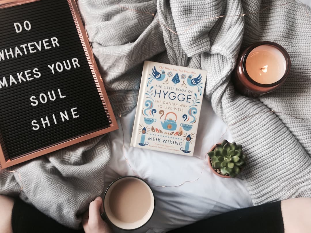 Cup of tea, candle, and hygge book on a bed