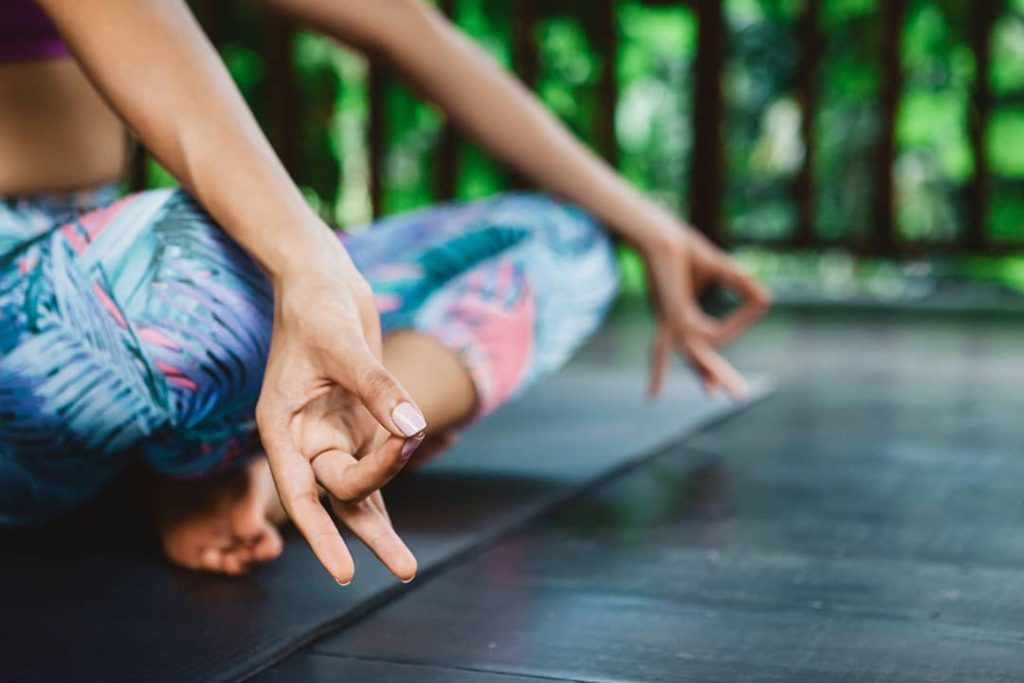 With her fingers in mudra, a young woman improves her well-being through meditation at a wellness retreat in Bali.
