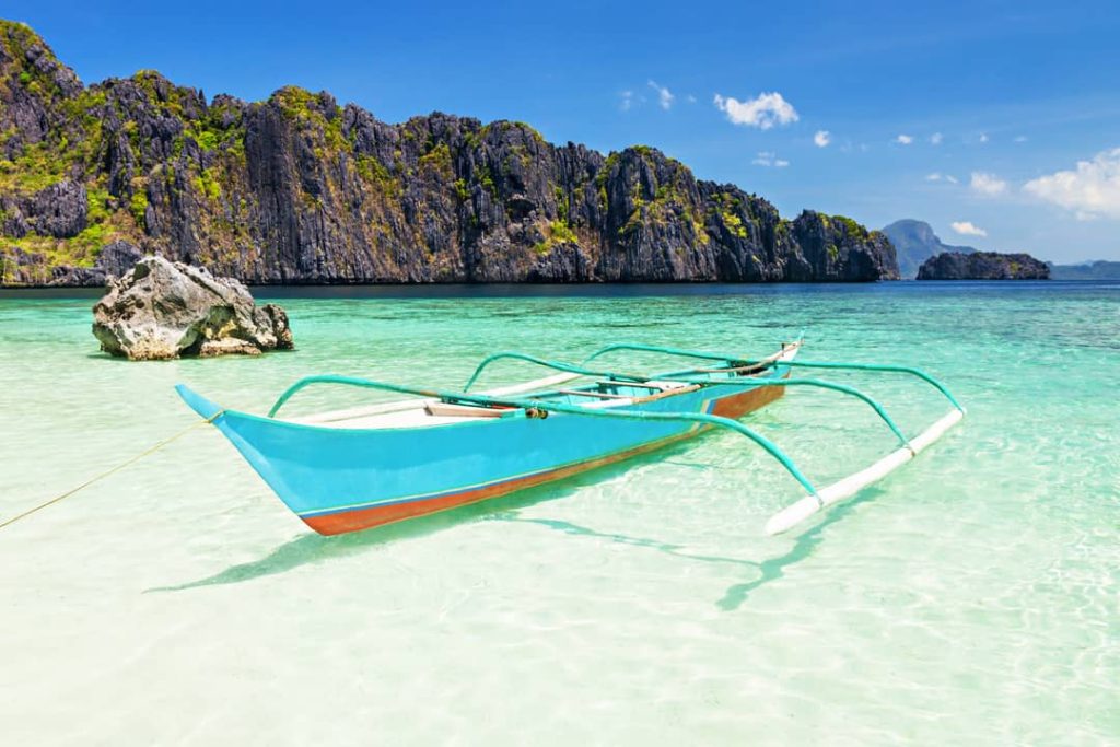 Improve your well-being in paradise. This image shows a classic Philippine spider boat tied up on the beach of El Nido, Philippines.